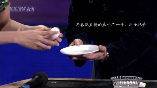 好了,這一動(dòng)作做完后,劉謙用左手接過董卿的戒指把玩一番,并問董卿這枚戒指有多貴,這一過程,劉謙很自然地把戒指放到了右手,注意,是塞到了右手的食指和拇指中間,因?yàn)橛沂值氖持负湍粗钢虚g已經(jīng)捏著個(gè)被皮筋拉扯的掛鉤,塞進(jìn)戒指后他用左手扭動(dòng)著戒指,好像在做下意識(shí)的動(dòng)作,其實(shí),是把戒指環(huán)掛到那個(gè)掛鉤上,這一動(dòng)作是在右手的食指和拇指“捏合”之中完成的,觀眾是看不到的,由于角度的原因,觀眾也看不到那根細(xì)細(xì)的皮筋.
